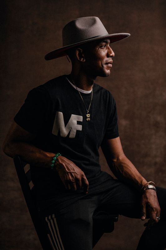 Mark Junius sits in profile wearing a large hat