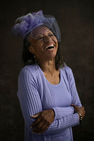 Sharon Asher throws her head back to laugh in lavender Sunday best