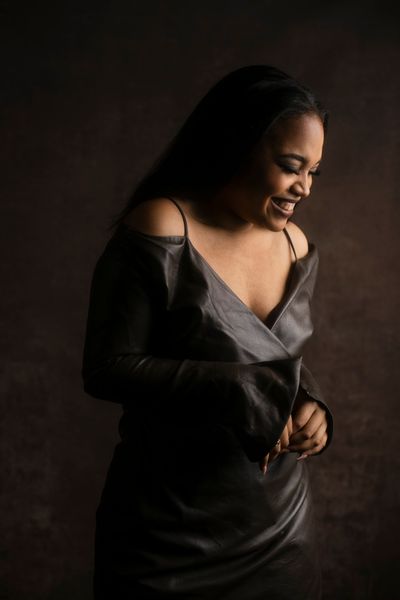 Ashley Jackson stands laughing toward the ground in a silky black dress