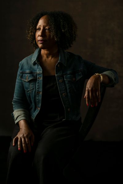 Diane Robertson sits in a denim jacket with her left arm resting on a chair back