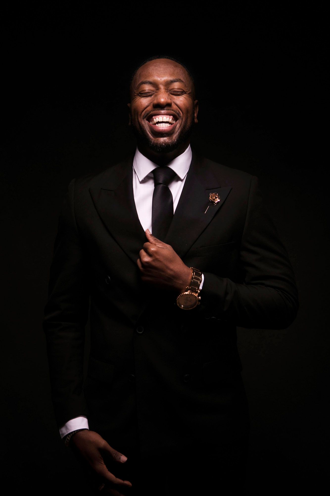 Pastor Michael J. Fisher stands smiling in a suit, grasping at his lapel