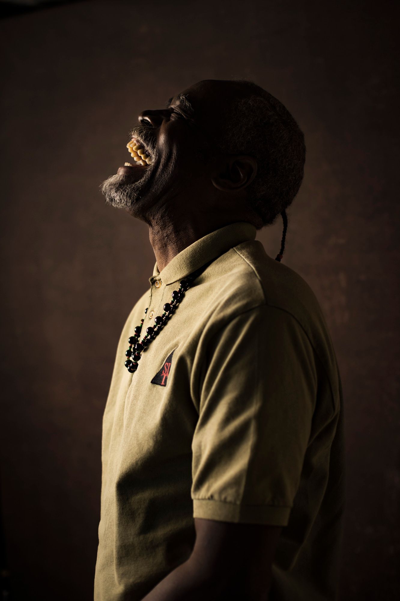 Paul E. Johnson throws his head back and laughs in a beige shirt and necklace