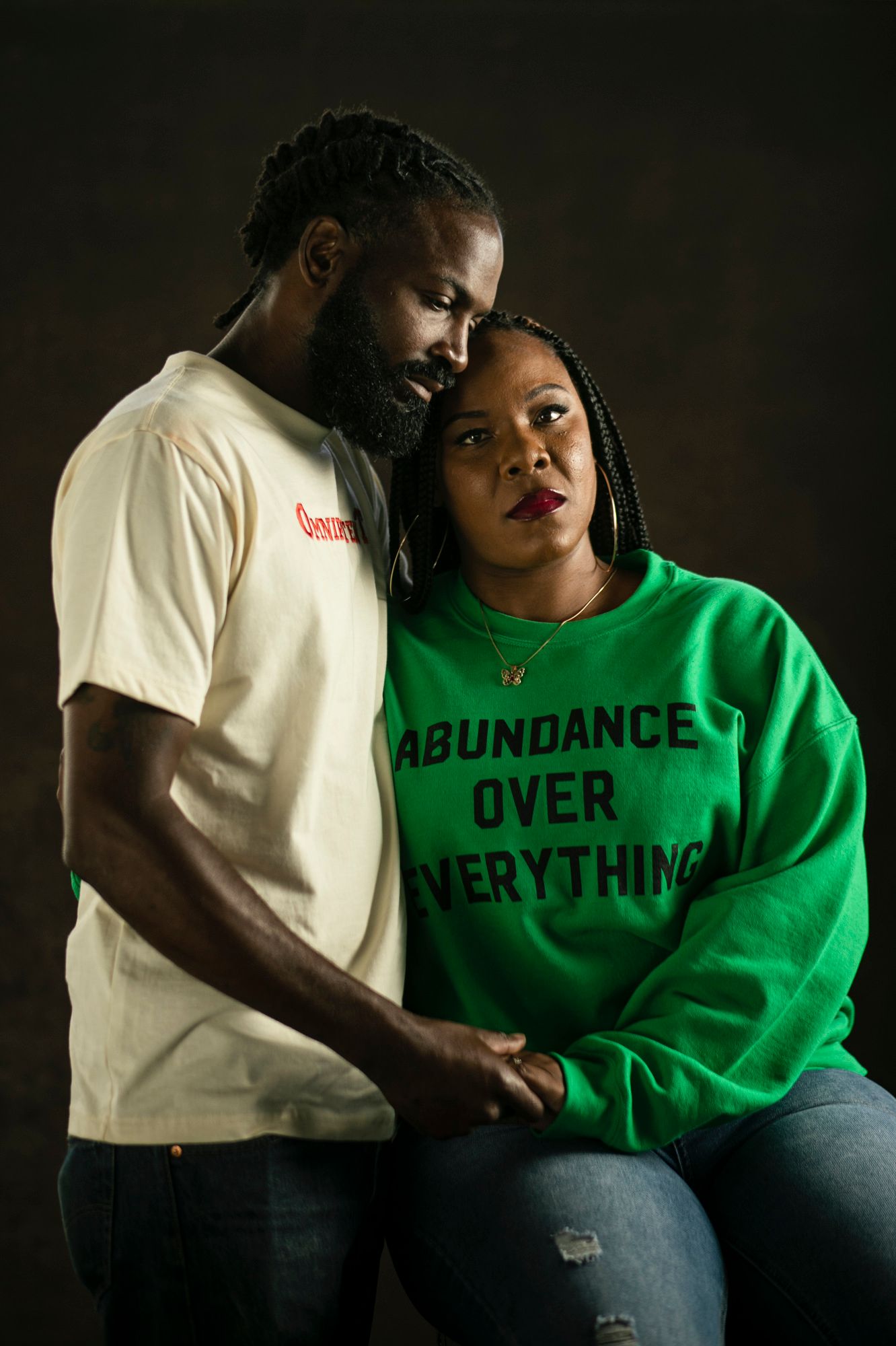 Armond Keys holds Lation Young as she sits next to him in a sweatshirt reading ABUNDANCE OVER EVERYTHING